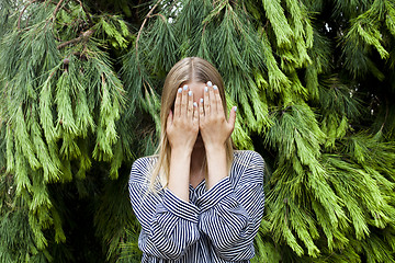 Image showing Beautiful young woman hiding her face standing in the forest aga