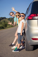 Image showing Happy brother and his two sisters are standing near the car at t
