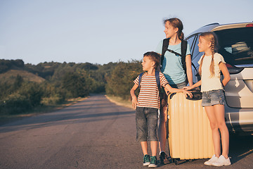 Image showing Happy brother and his two sisters are standing near the car at t