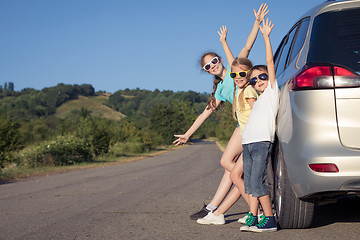 Image showing Happy brother and his two sisters are standing near the car at t