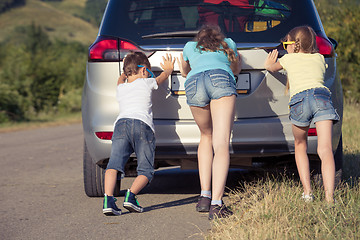 Image showing Happy brother and his two sisters are standing near the car at t