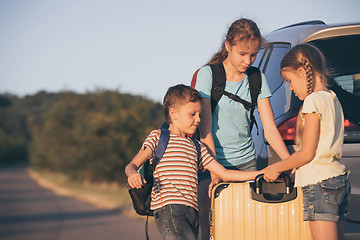 Image showing Happy brother and his two sisters are standing near the car at t