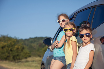 Image showing Happy brother and his two sisters are standing near the car at t