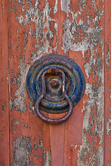 Image showing Italian door knocker on old wooden red background.