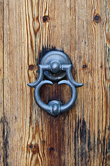 Image showing Italian door knocker on old wooden brown background.