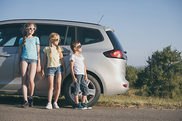 Image showing Happy brother and his two sisters are standing near the car at t