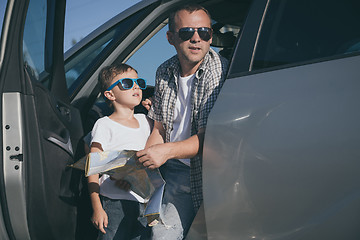 Image showing Happy father and son standing near the car at the day time.