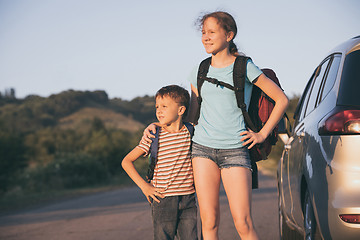 Image showing Happy brother and his  sister are standing near the car at the d