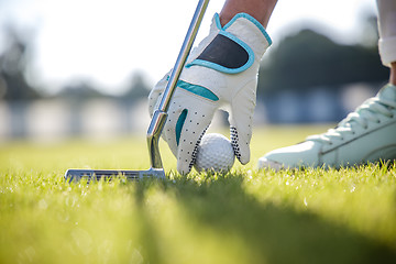 Image showing Hand in glove placing golf ball on tee