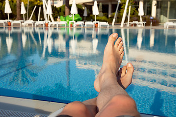 Image showing Men\'s feet on the background of the swimming pool, relax on vaca