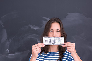 Image showing woman holding a banknote in front of chalk drawing board