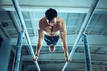 Image showing The sportsman during difficult exercise, sports gymnastics