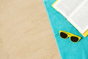 Image showing sunglasses and book on beach towel on sand