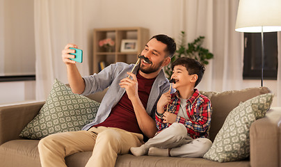 Image showing father and son taking selfie at home