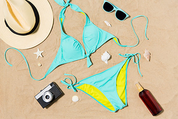 Image showing bikini, hat, camera and sunglasses on beach sand