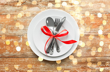 Image showing cutlery tied with red ribbon on set of plates