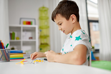 Image showing little boy playing with building kit at home