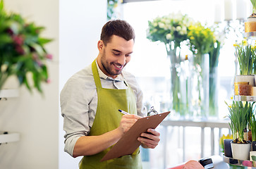 Image showing florist man with clipboard at flower shop counter