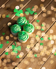 Image showing green cupcakes and shamrock on wooden table