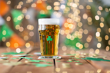 Image showing glass of beer with shamrock and coins on table