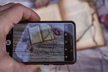 Image showing Book And Autumn Leaves Through Smartphone