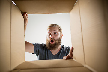 Image showing Man unpacking and opening carton box and looking inside