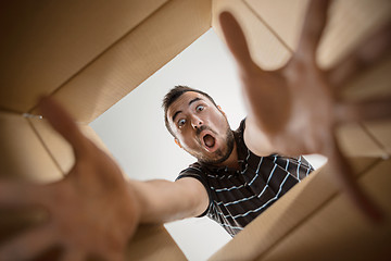 Image showing Man unpacking and opening carton box and looking inside