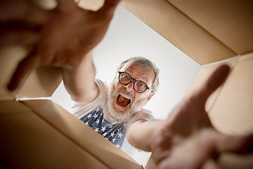 Image showing Man unpacking and opening carton box and looking inside