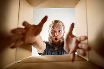 Image showing Man unpacking and opening carton box and looking inside