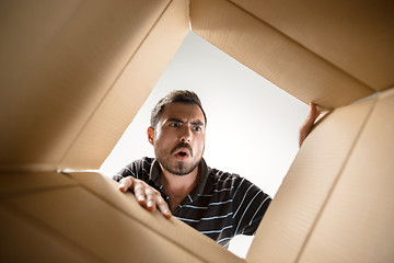 Image showing Man unpacking and opening carton box and looking inside