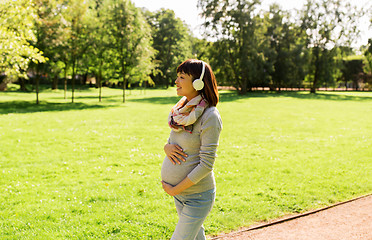 Image showing happy pregnant asian woman in headphones at park