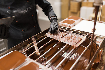 Image showing confectioner removing excess chocolate from mold