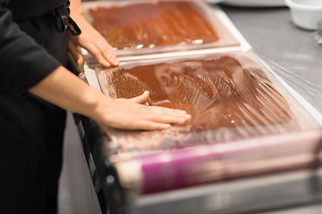 Image showing confectioner makes chocolate dessert at sweet-shop