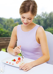 Image showing smiling young woman eating dessert at restaurant