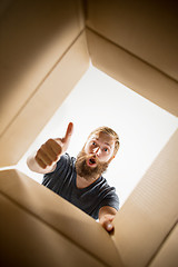 Image showing Man unpacking and opening carton box and looking inside