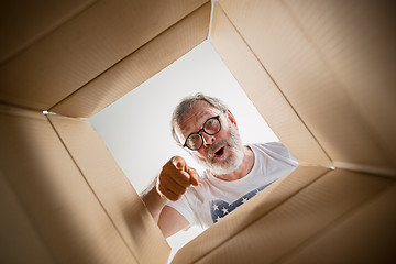 Image showing Man unpacking and opening carton box and looking inside