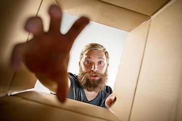 Image showing Man unpacking and opening carton box and looking inside