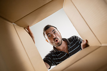 Image showing Man unpacking and opening carton box and looking inside