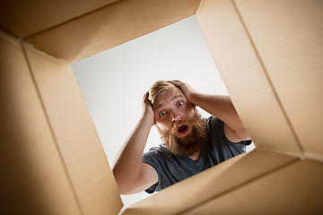 Image showing Man unpacking and opening carton box and looking inside