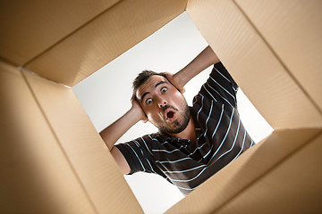 Image showing Man unpacking and opening carton box and looking inside