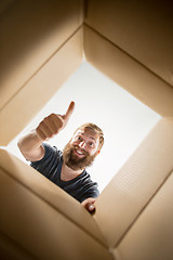 Image showing Man unpacking and opening carton box and looking inside