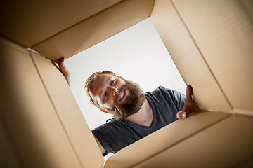 Image showing Man unpacking and opening carton box and looking inside