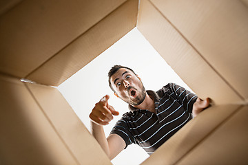 Image showing Man unpacking and opening carton box and looking inside