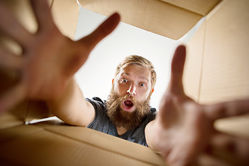 Image showing Man unpacking and opening carton box and looking inside