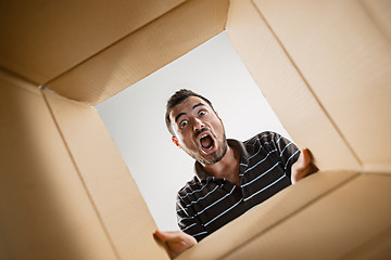 Image showing Man unpacking and opening carton box and looking inside