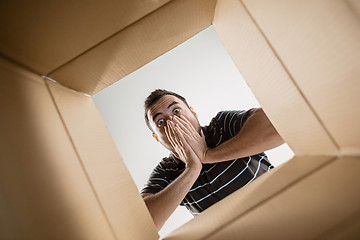 Image showing Man unpacking and opening carton box and looking inside