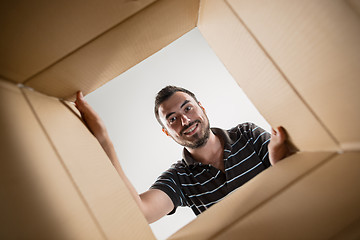 Image showing Man smiling, unpacking and opening carton box and looking inside