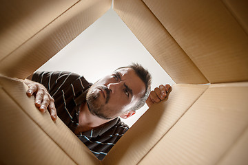 Image showing Man unpacking and opening carton box and looking inside