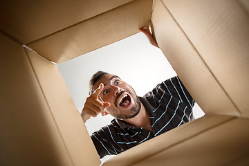 Image showing Man unpacking and opening carton box and looking inside