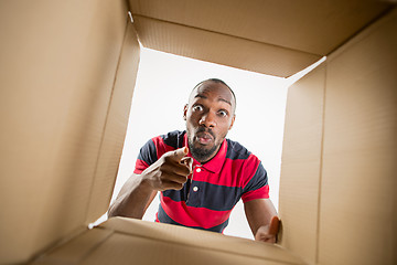 Image showing Man unpacking and opening carton box and looking inside